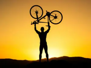 cycliste face triomphant face à un couché de soleil
